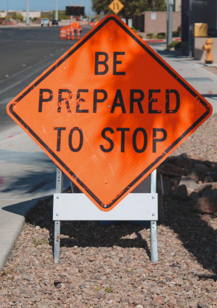 An orange "Be Prepared To Stop" roadwork sign on Warm Springs Road.